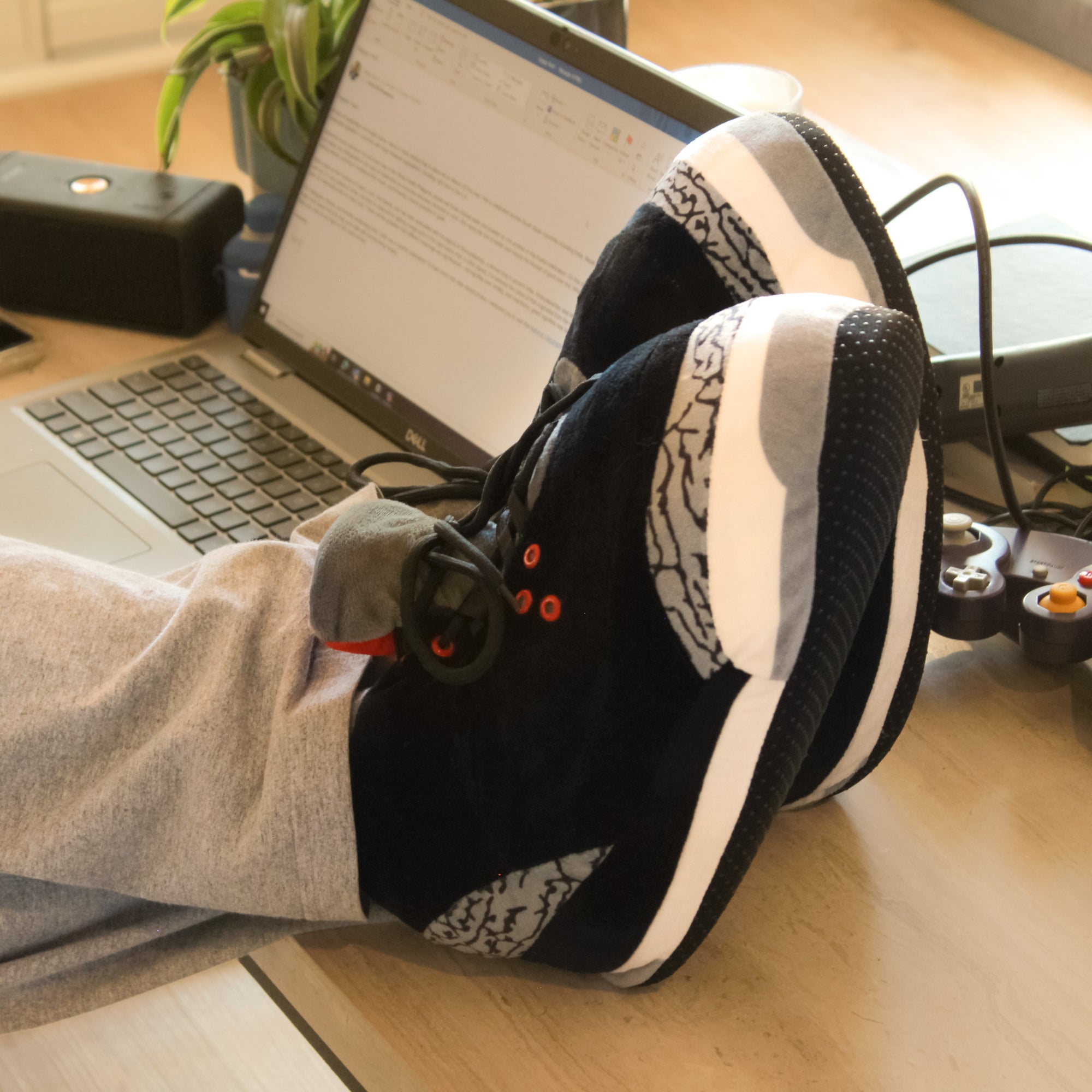 Model wearing Yours 2 Keep Black Marble Sneaker Slippers with feet up on coffee table